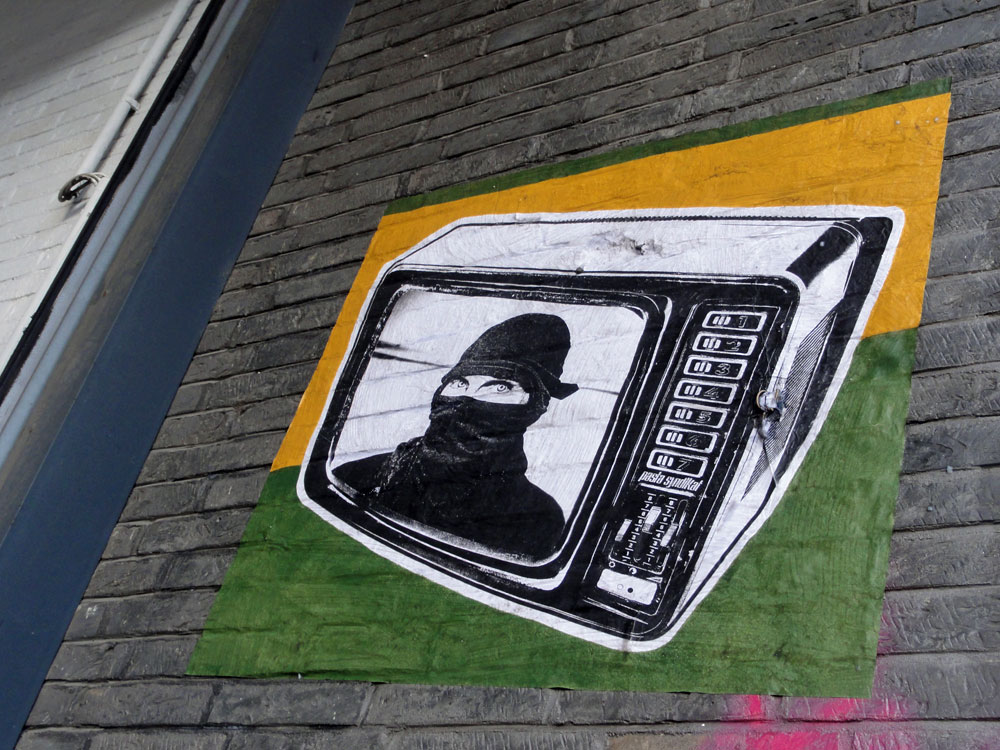 Streetart in Frankfurt: Paste Up mit vermummten Mann im Fernseher