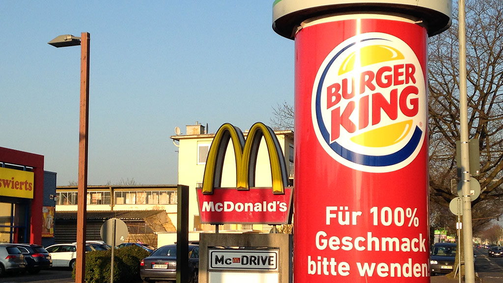 Burger King-Werbung bei Mc Donald's-Restaurant in Frankfurt.