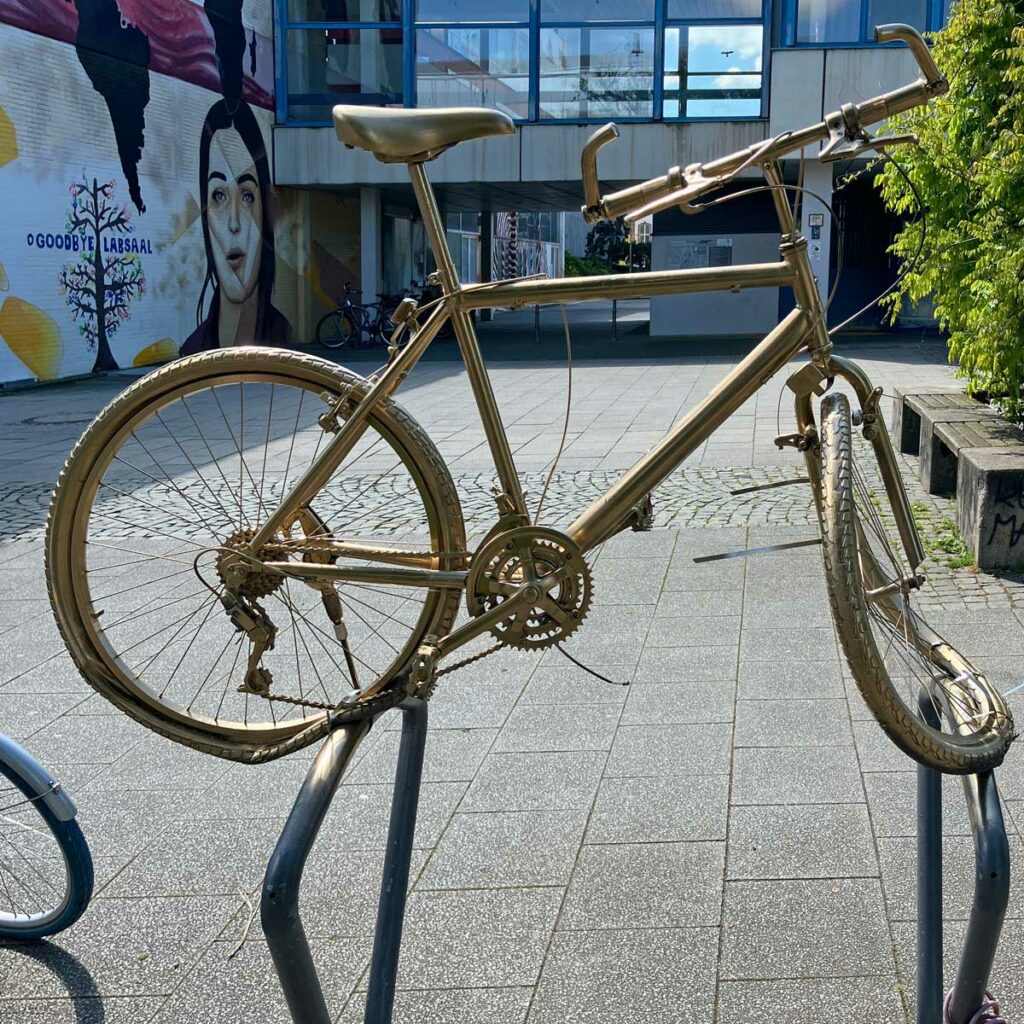 Auf Fahrradbügeln befestigtes goldenes Fahrrad in Frankfurt