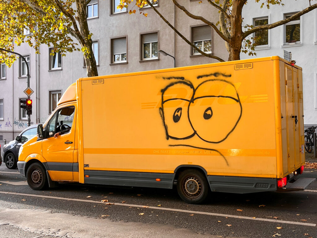 Gelber Transporter mit stilisiertem Gesicht mit großen Augen und nach unten gerichteten Augenbrauen und Mundlinien