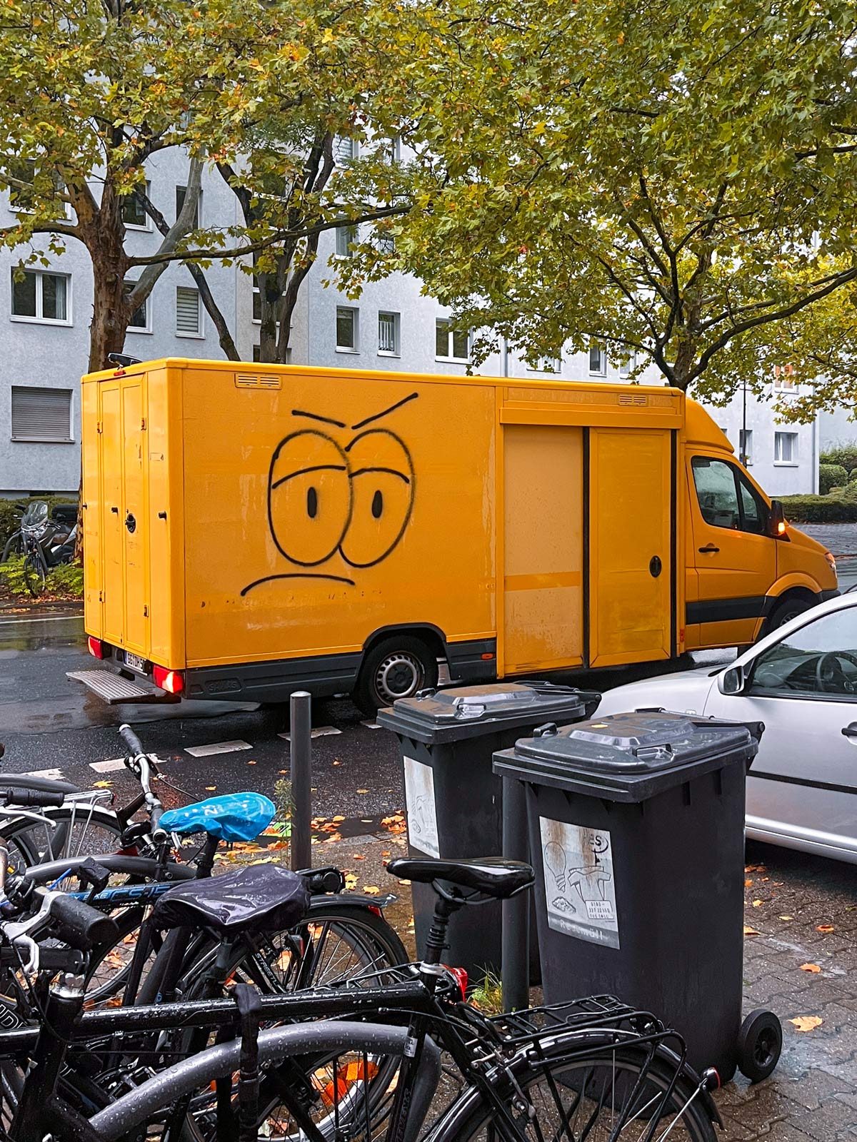 Gelber Transporter mit stilisiertem Gesicht mit großen Augen und nach unten gerichteten Augenbrauen und Mundlinien