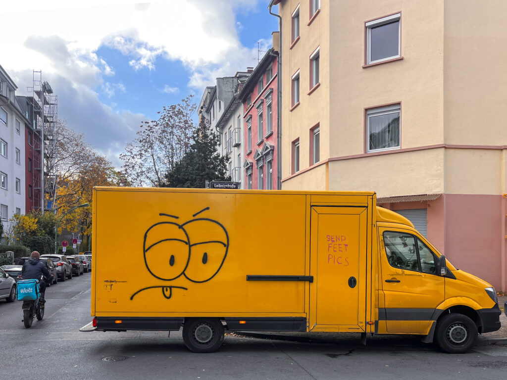 Gelber Transporter mit stilisiertem Gesicht mit großen Augen und nach unten gerichteten Augenbrauen und Mundlinien