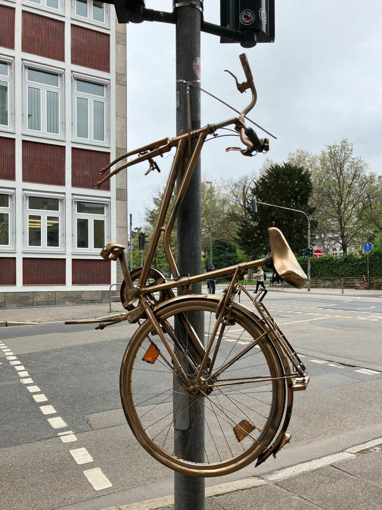 Goldenes Fahrrad hochkant befestigt an Ampelmast in Frankfurt