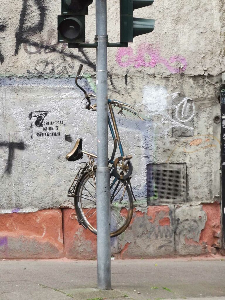 Goldenes Fahrrad hochkant befestigt an Ampelmast in Frankfurt