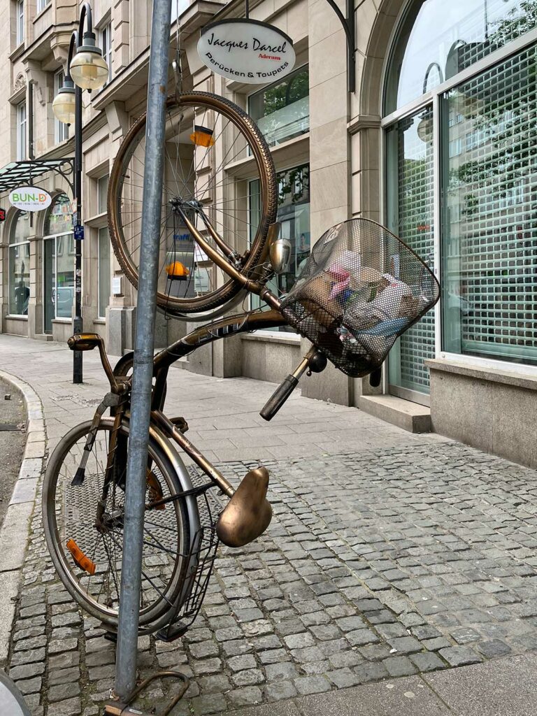 Goldenes Fahrrad hochkant befestigt an Straßenschild befestigt in Frankfurt