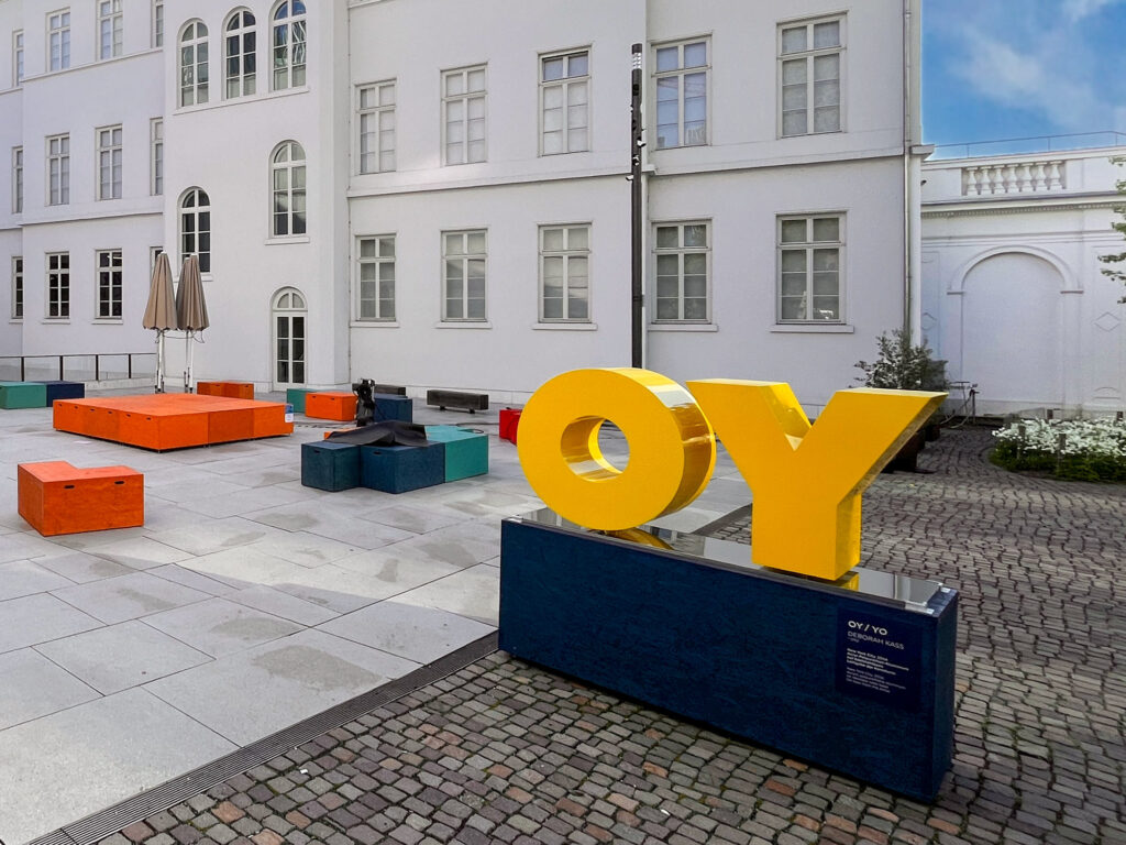 Gelbe Buchstaben auf blauem Podest – OY / YO von Deborah Kass vor dem Jüdischen Museum Frankfurt
