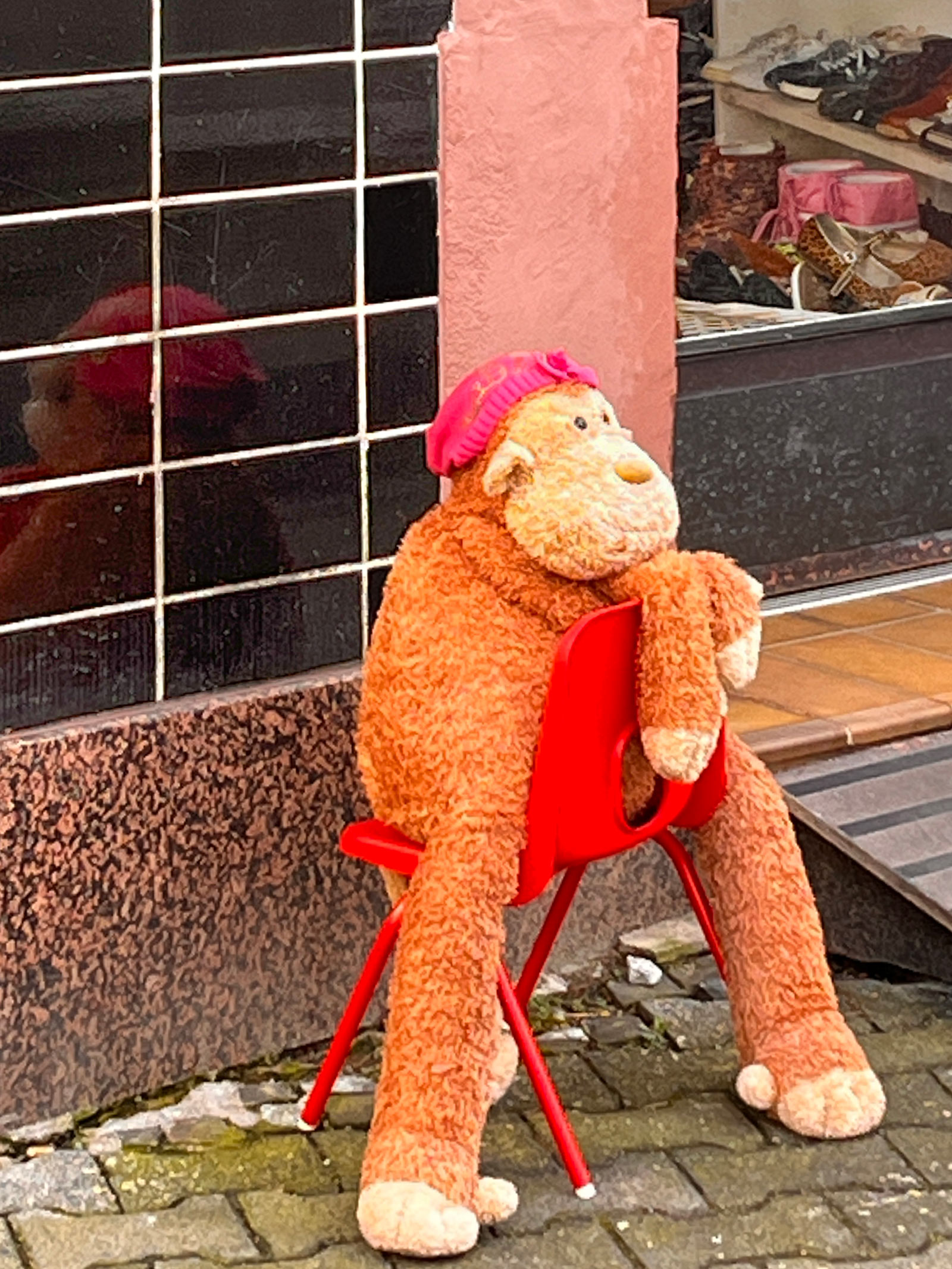 Stadtbilder Frankfurt – Großer Stofftier-Affe im Stuhl vor einem Geschäft in Sachsehausen