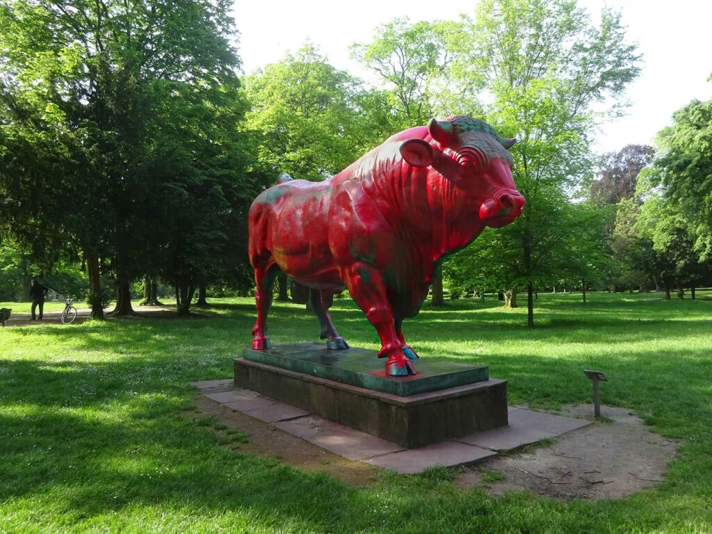 Stier-Skulptur im Günthersburgpark mit roter Rabe