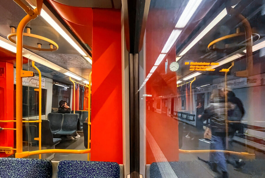 In einer U-Bahn in Frankfurt sitzend. Die eine Hälfte des Fotos zeigt das Innere des Waggons, die andere Hälfte dessen Spiegelung an der Fensterscheibe.