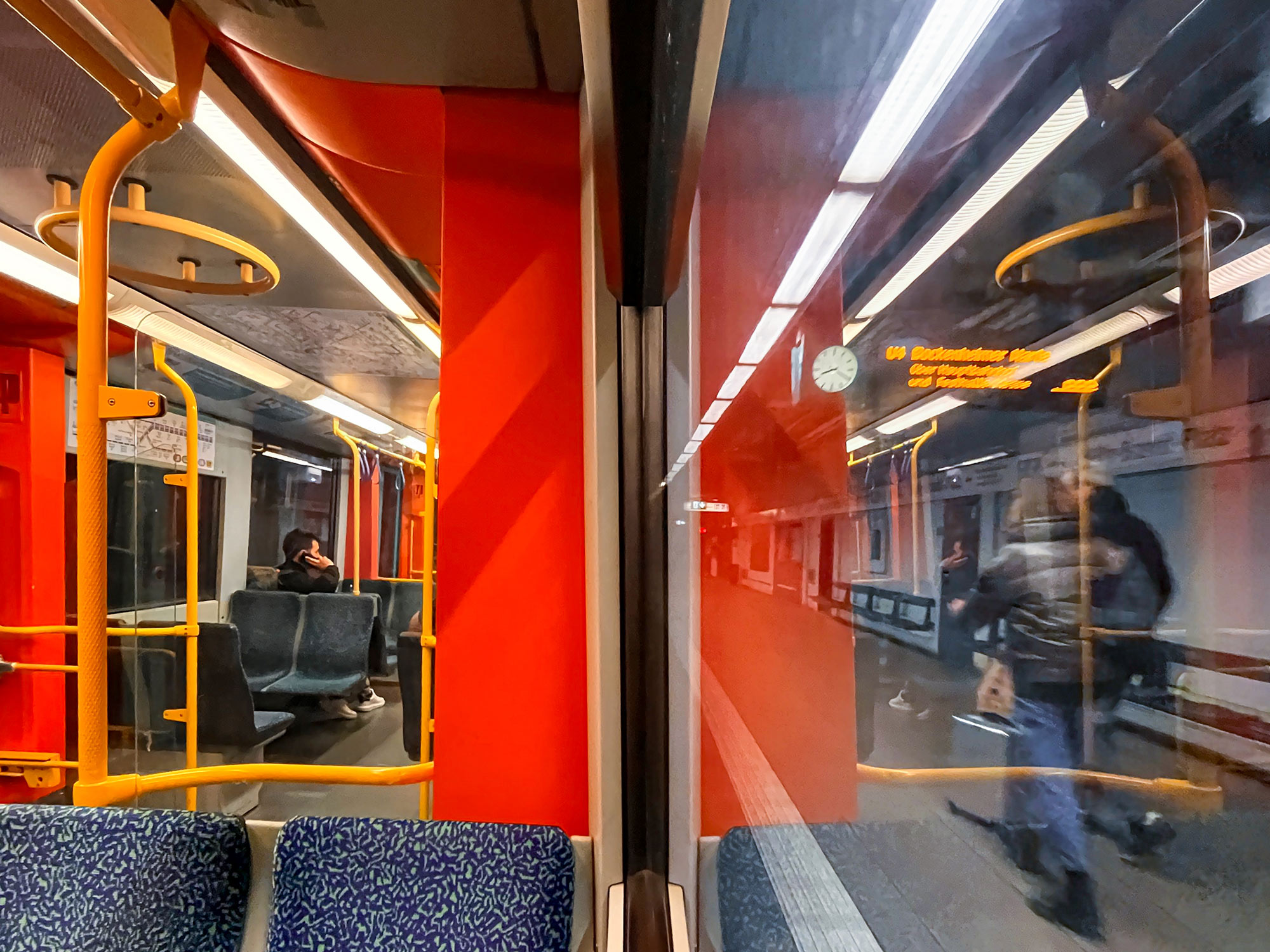 In einer U-Bahn in Frankfurt sitzend. Die eine Hälfte des Fotos zeigt das Innere des Waggons, die andere Hälfte dessen Spiegelung an der Fensterscheibe.
