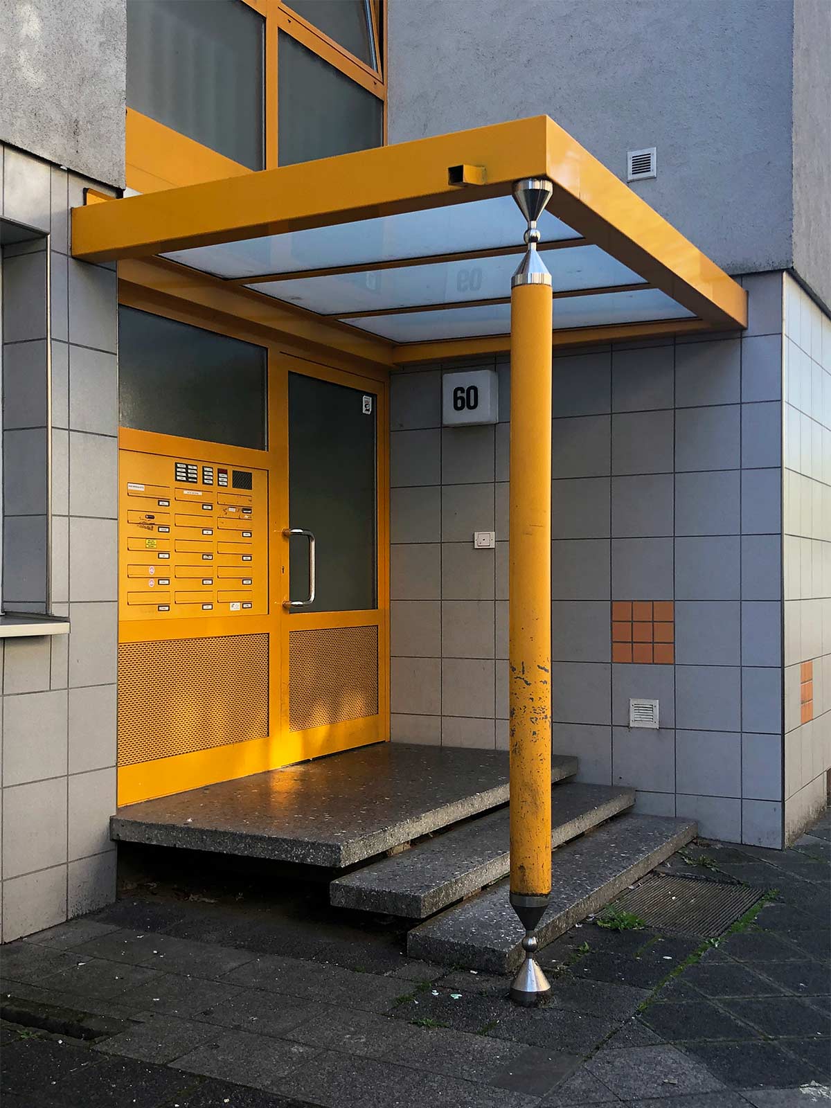 Vordach und Stützsäule in gelber Farbe an Wohnhaus in Offenbach