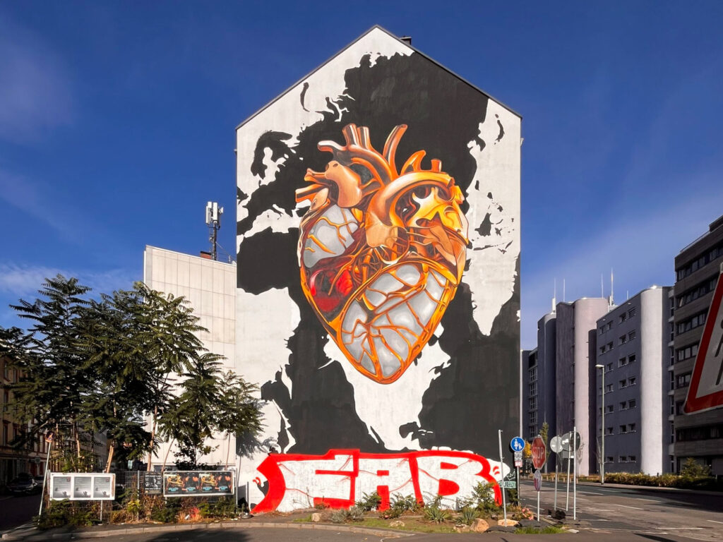 Wände im Wandel – Übermalte Murals und Wandbilder in der Urban Art, hier: übersprüht mit großem Name am unteren Ende des Murals.
